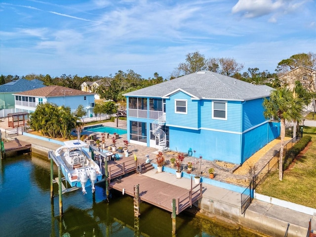 rear view of house with a sunroom, a patio area, a water view, and a balcony