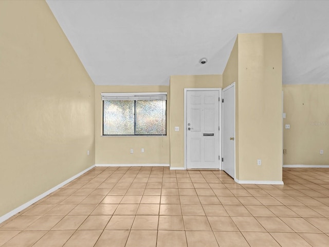 empty room with light tile patterned flooring and lofted ceiling