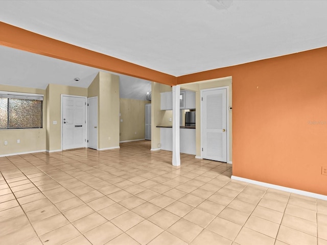 empty room with lofted ceiling with beams and light tile patterned floors