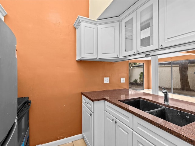 kitchen featuring light tile patterned flooring, white cabinetry, sink, and dark stone counters