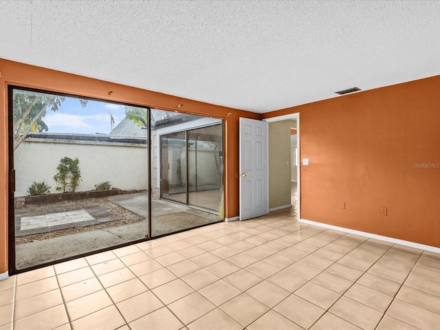 tiled empty room featuring a textured ceiling