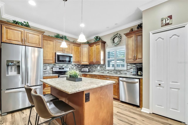 kitchen featuring light stone countertops, a center island, hanging light fixtures, a breakfast bar area, and appliances with stainless steel finishes