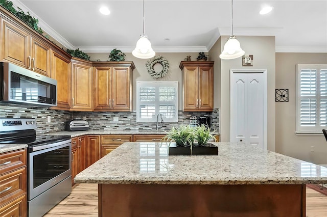 kitchen with decorative backsplash, crown molding, a kitchen island, and appliances with stainless steel finishes