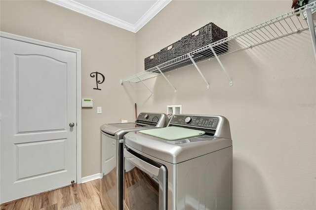 laundry room featuring crown molding, washer and clothes dryer, and light wood-type flooring