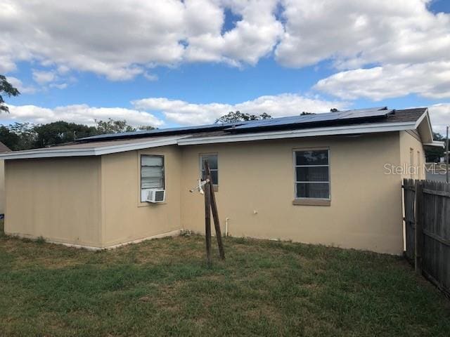 view of side of home with a lawn and solar panels