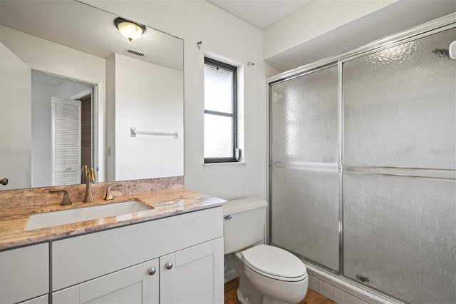 bathroom with vanity, toilet, and a shower with shower door