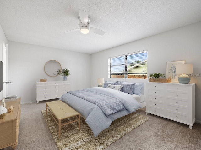 bedroom with ceiling fan, light colored carpet, and a textured ceiling