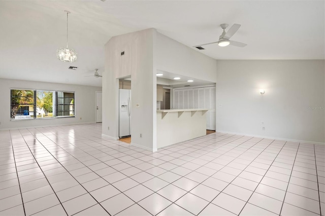 unfurnished living room with lofted ceiling, ceiling fan with notable chandelier, and light tile patterned floors