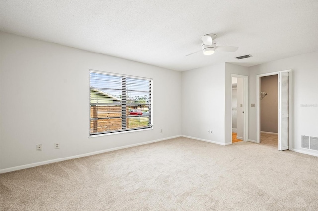 carpeted empty room featuring ceiling fan and a textured ceiling