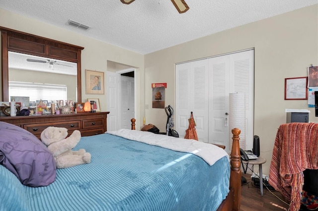 bedroom with a textured ceiling, ceiling fan, and dark hardwood / wood-style floors