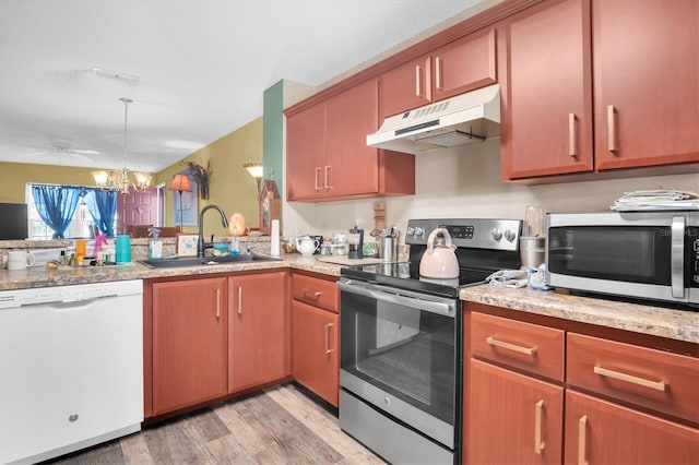 kitchen with sink, stainless steel appliances, pendant lighting, light hardwood / wood-style floors, and ceiling fan with notable chandelier