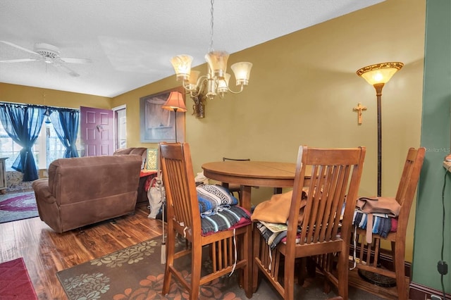 dining room with a textured ceiling, hardwood / wood-style floors, and ceiling fan with notable chandelier