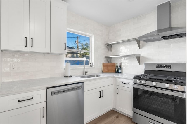 kitchen featuring white cabinetry, sink, light hardwood / wood-style floors, stainless steel appliances, and wall chimney exhaust hood