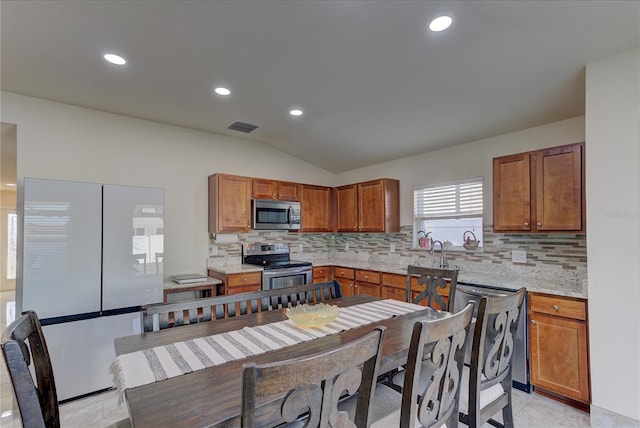 kitchen featuring stainless steel appliances, tasteful backsplash, lofted ceiling, and light tile patterned flooring