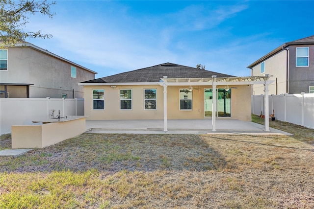 back of property featuring ceiling fan, a patio area, an outdoor bar, and a yard