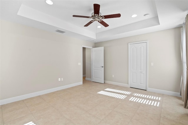 unfurnished bedroom with ceiling fan, a raised ceiling, and light tile patterned floors