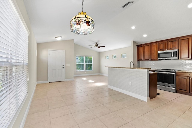 kitchen with light tile patterned flooring, backsplash, appliances with stainless steel finishes, and vaulted ceiling