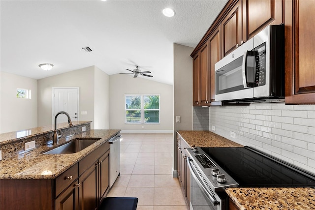 kitchen featuring vaulted ceiling, appliances with stainless steel finishes, sink, light tile patterned floors, and light stone countertops