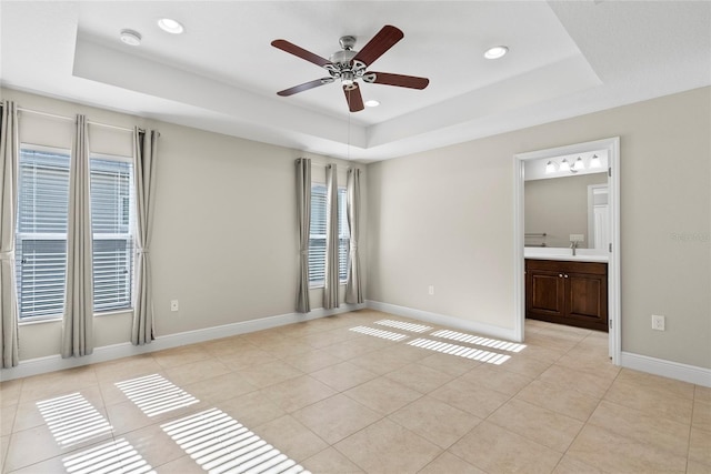 spare room featuring ceiling fan, light tile patterned floors, and a raised ceiling