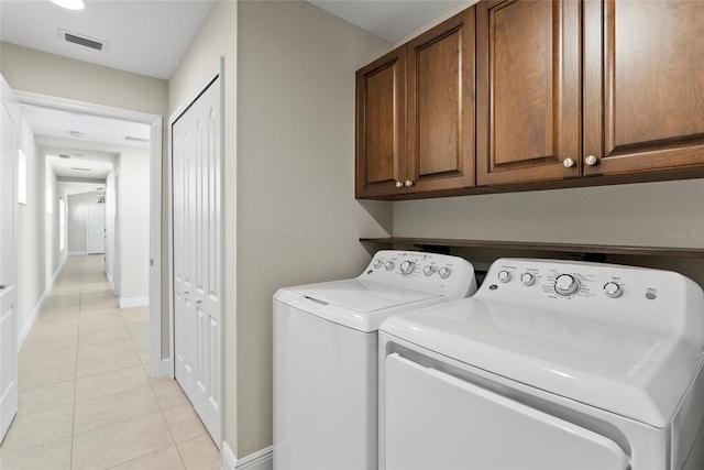 laundry area with cabinets, separate washer and dryer, and light tile patterned floors