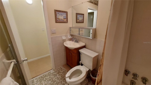 bathroom with tile patterned floors, vanity, toilet, and tile walls