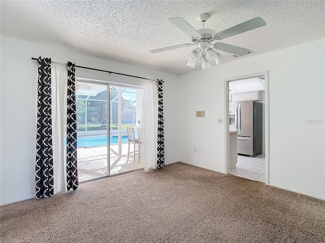 carpeted spare room with a textured ceiling and ceiling fan