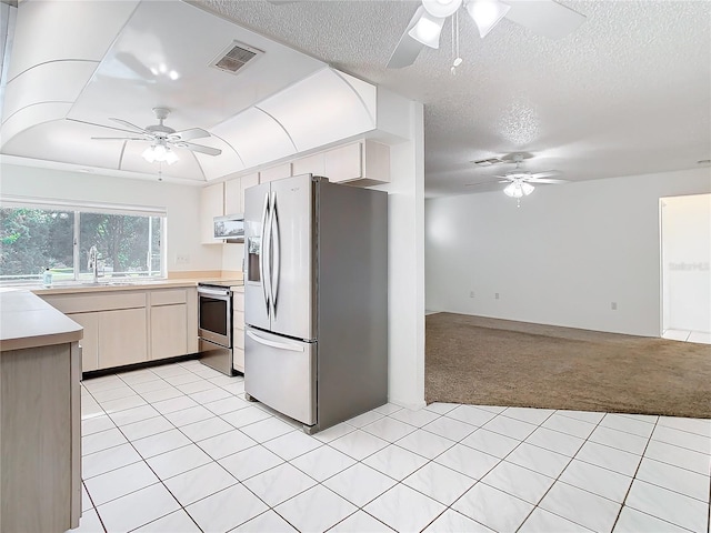 kitchen with sink, light colored carpet, a textured ceiling, exhaust hood, and appliances with stainless steel finishes