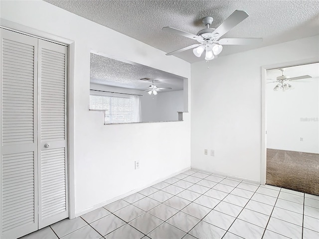 unfurnished bedroom with ceiling fan, light tile patterned floors, a textured ceiling, and a closet