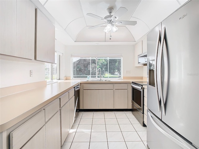 kitchen with kitchen peninsula, stainless steel appliances, ceiling fan, sink, and light tile patterned floors