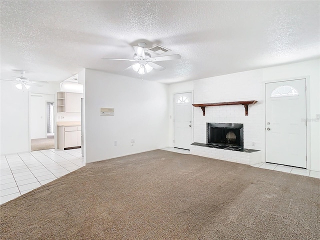 unfurnished living room featuring light colored carpet, a textured ceiling, and a brick fireplace