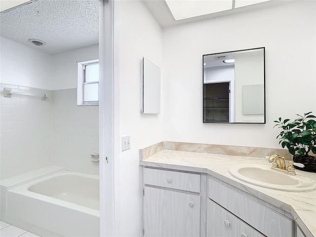 bathroom with tile patterned floors, vanity, a textured ceiling, and tiled shower / bath