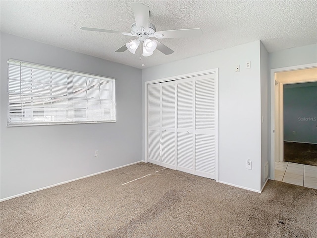 unfurnished bedroom with ceiling fan, carpet floors, a textured ceiling, and a closet