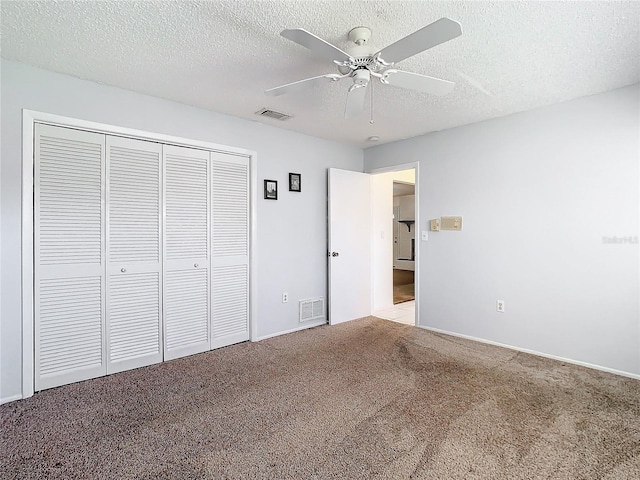 unfurnished bedroom featuring a closet, a textured ceiling, light colored carpet, and ceiling fan