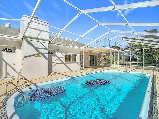 view of pool featuring glass enclosure, ceiling fan, and a patio area