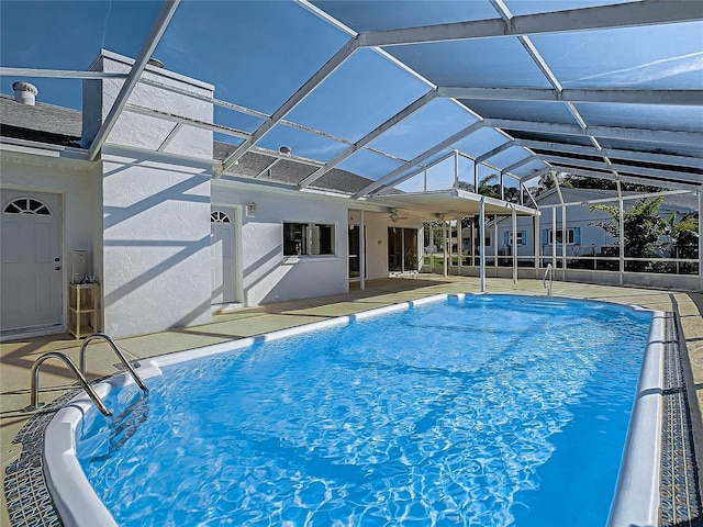 view of pool with a patio, glass enclosure, and ceiling fan