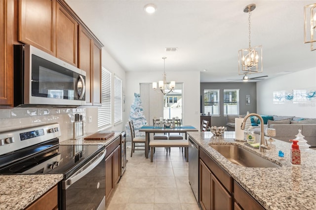 kitchen with appliances with stainless steel finishes, ceiling fan with notable chandelier, hanging light fixtures, and sink
