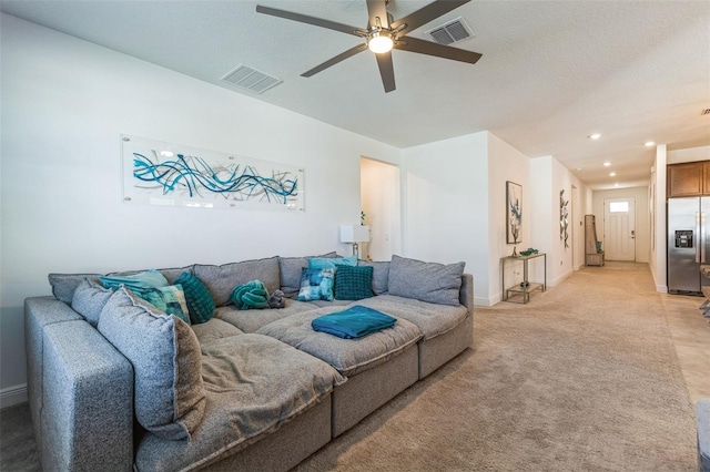 living room with a textured ceiling, light colored carpet, and ceiling fan