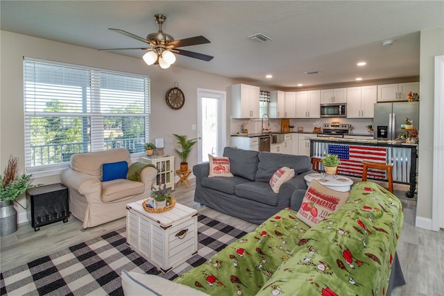 living room featuring ceiling fan, a healthy amount of sunlight, and light hardwood / wood-style flooring