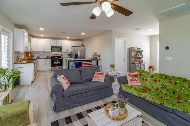 living room with ceiling fan and light hardwood / wood-style floors