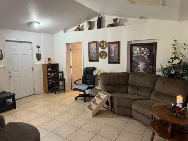 living room with light tile patterned floors and vaulted ceiling