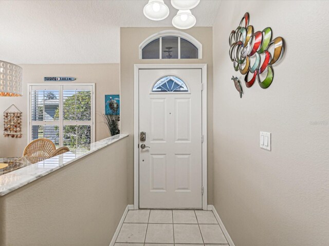 doorway to outside with a textured ceiling and light tile patterned floors