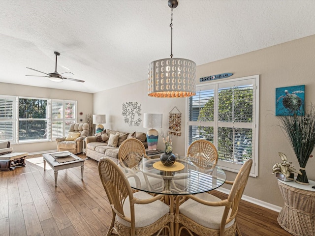 dining room featuring wood-type flooring, ceiling fan, and a textured ceiling