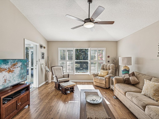 living room with ceiling fan, wood-type flooring, vaulted ceiling, and a textured ceiling