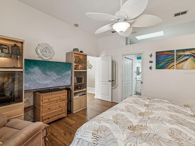 bedroom featuring hardwood / wood-style floors, vaulted ceiling with skylight, and ceiling fan