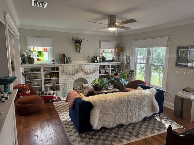 living room with dark hardwood / wood-style floors, ceiling fan, ornamental molding, and a brick fireplace