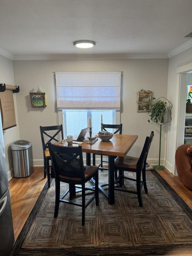 dining space with a healthy amount of sunlight, dark wood-type flooring, and ornamental molding