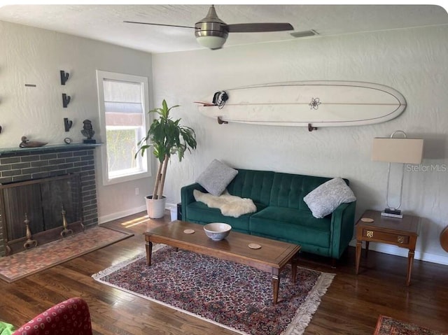 living room with ceiling fan, dark wood-type flooring, and a brick fireplace