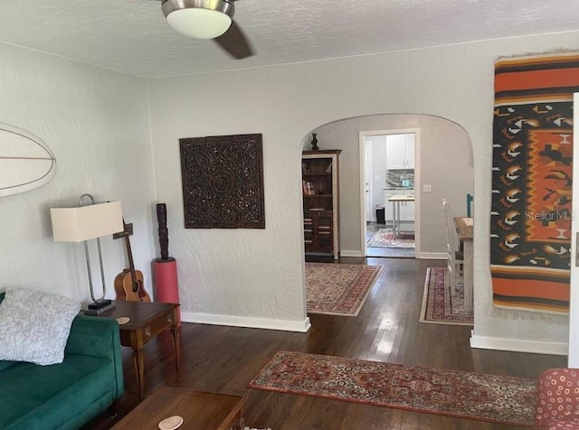 living room with ceiling fan, dark hardwood / wood-style flooring, and a textured ceiling