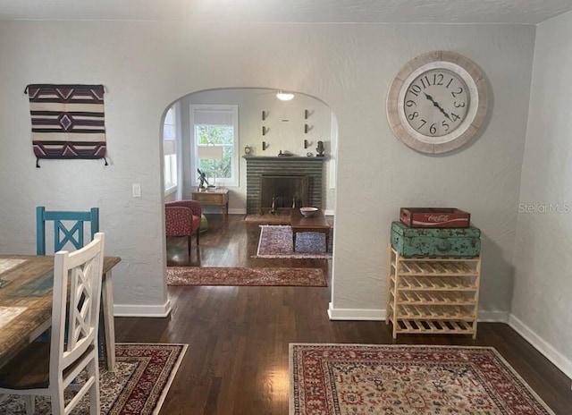 dining room featuring dark wood-type flooring and a brick fireplace