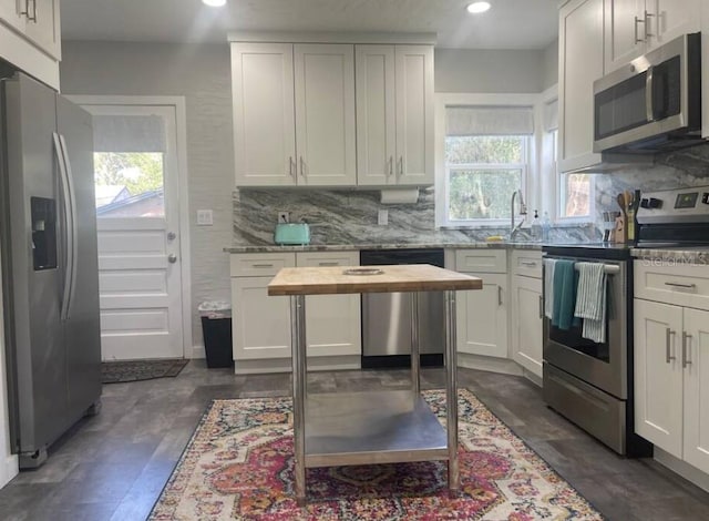 kitchen featuring white cabinets, a wealth of natural light, light stone counters, and appliances with stainless steel finishes